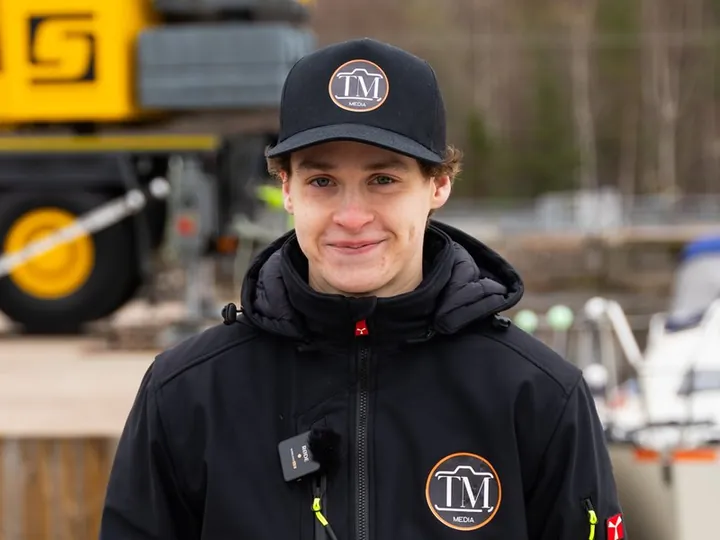 Felix Thomasson lippiksessä ja takissa, jossa on TM Median logo